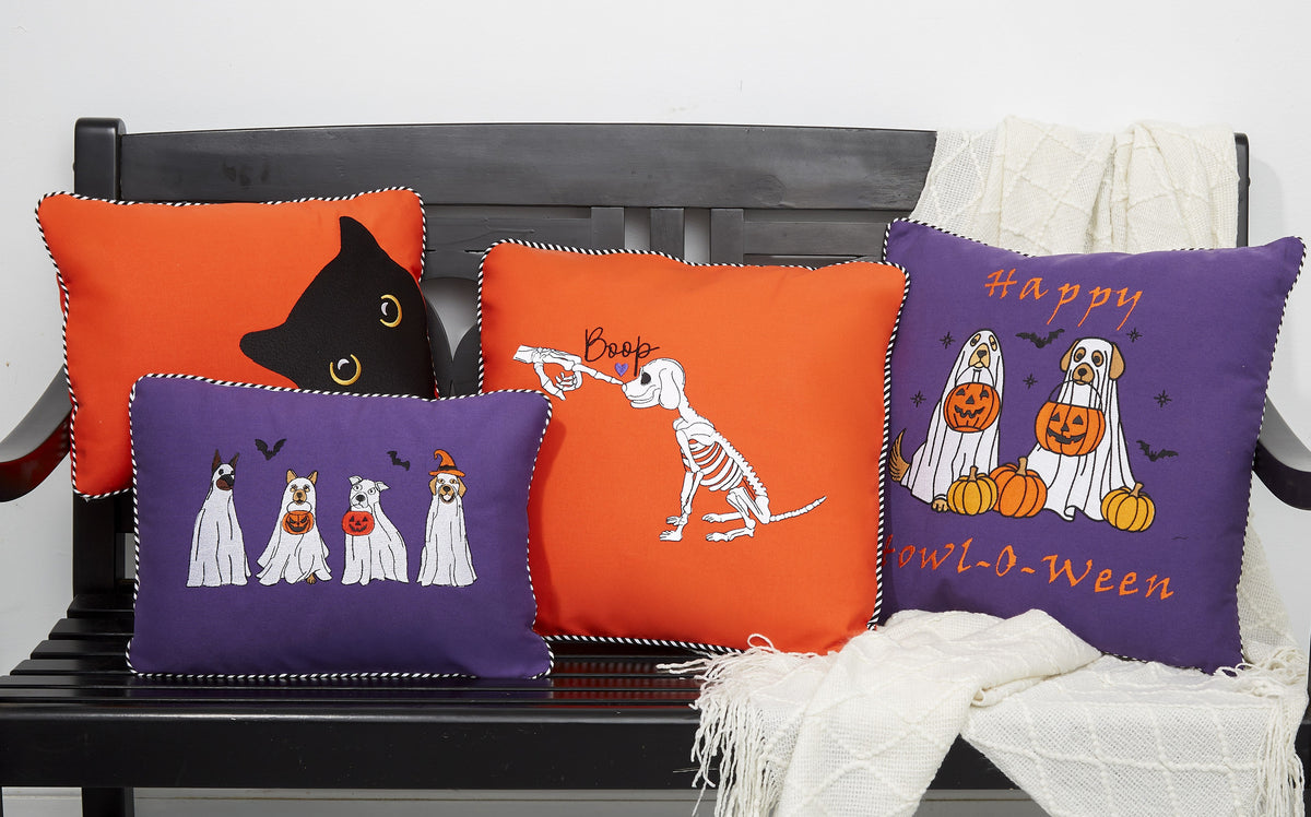 Halloween-themed decorative pillows on a black bench with a white background